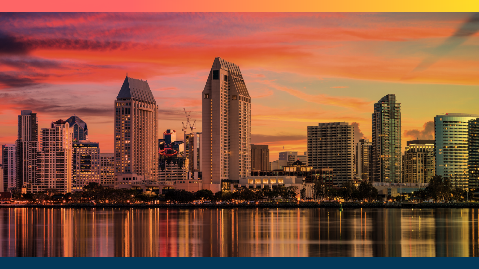 The San Diego skyline at sunset, featuring tall modern buildings reflecting off the calm waterfront. The sky is painted in vivid shades of orange, pink, and yellow, with streaks of clouds adding texture. A gradient border in warm tones frames the top of the image, while a deep blue band anchors the bottom.