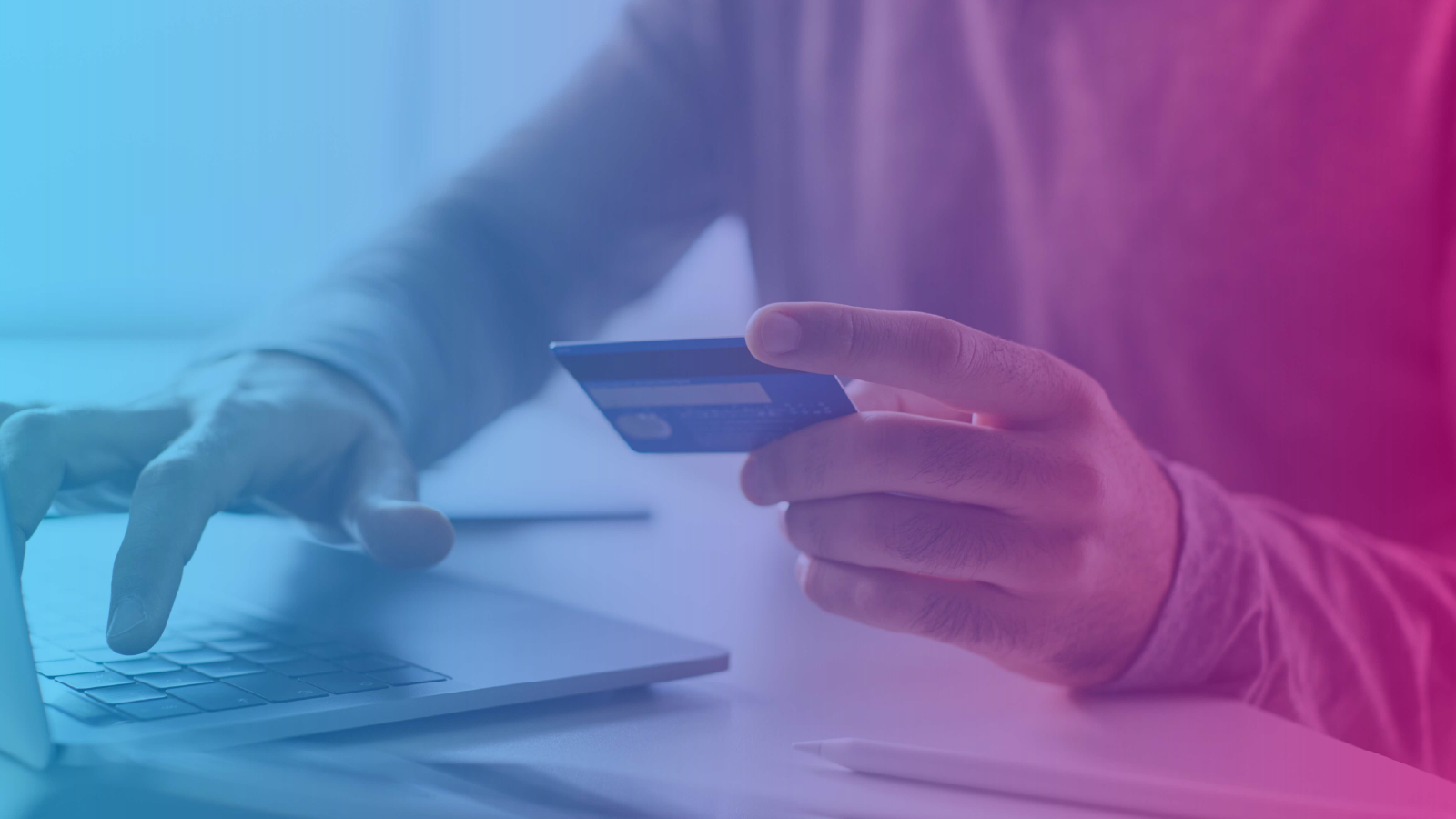 Person holding a credit card while using a laptop, with a blue-to-pink gradient overlay.