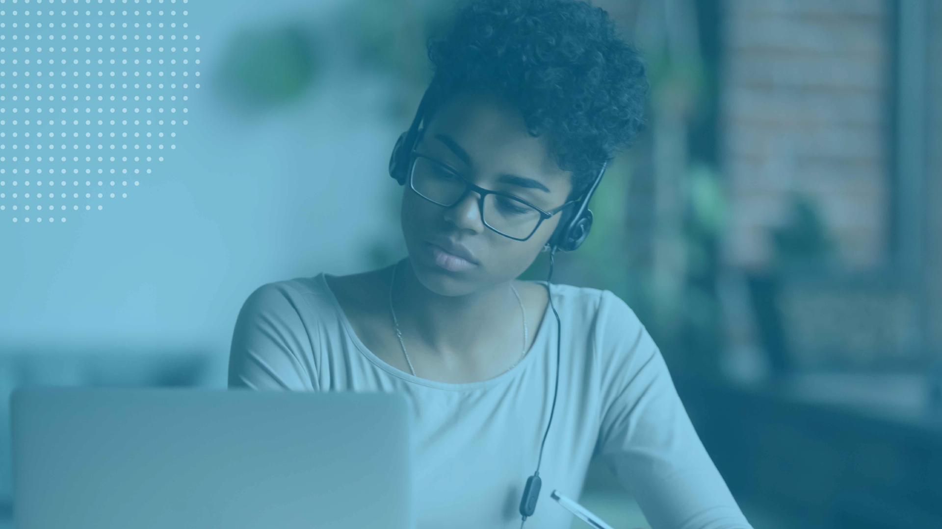 Professional wearing a headset and glasses, focused on a laptop during an online webinar or virtual learning session.