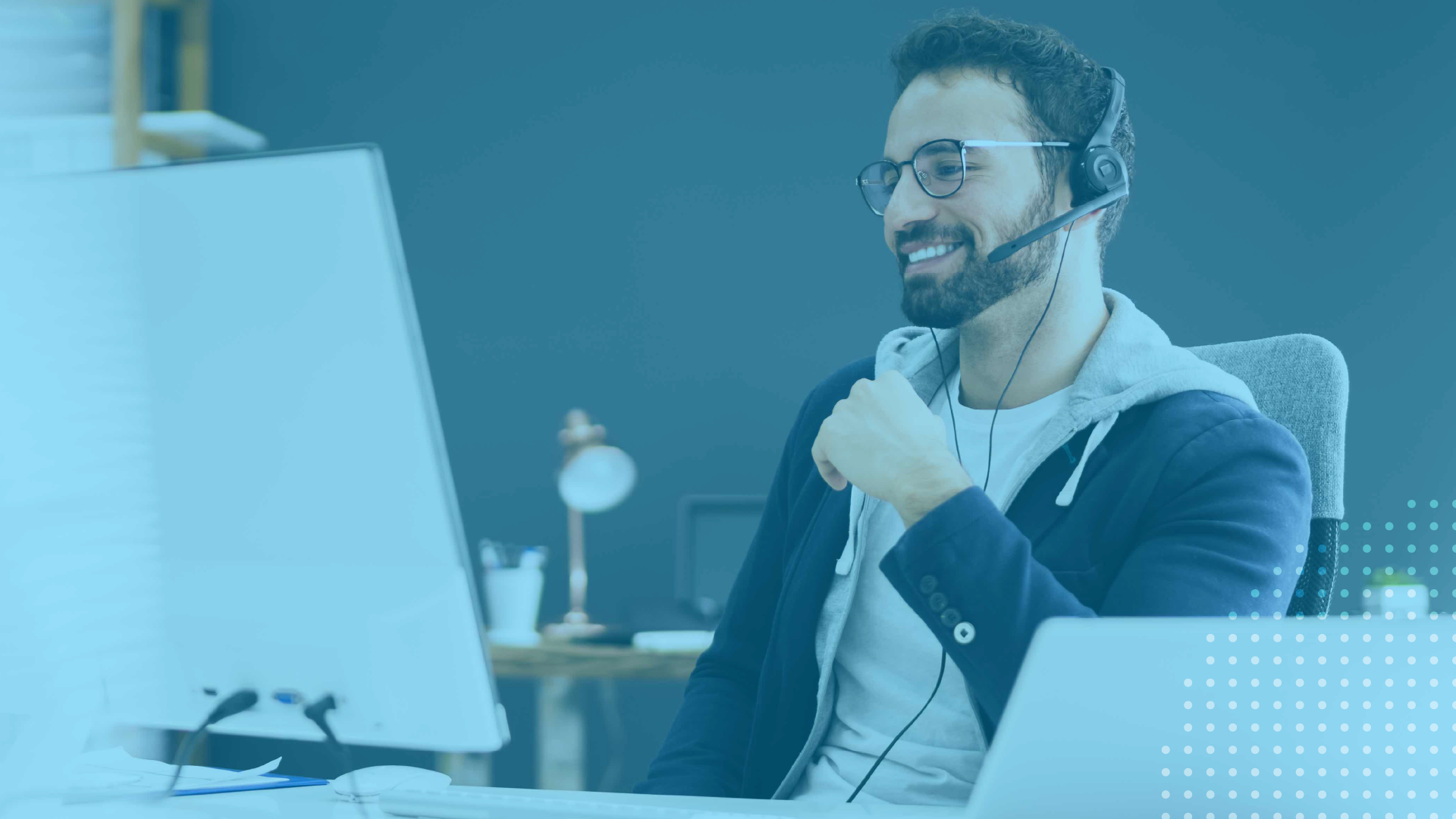 Professional wearing a headset and smiling while participating in a virtual webinar from a desk, with a computer monitor visible in a modern workspace.